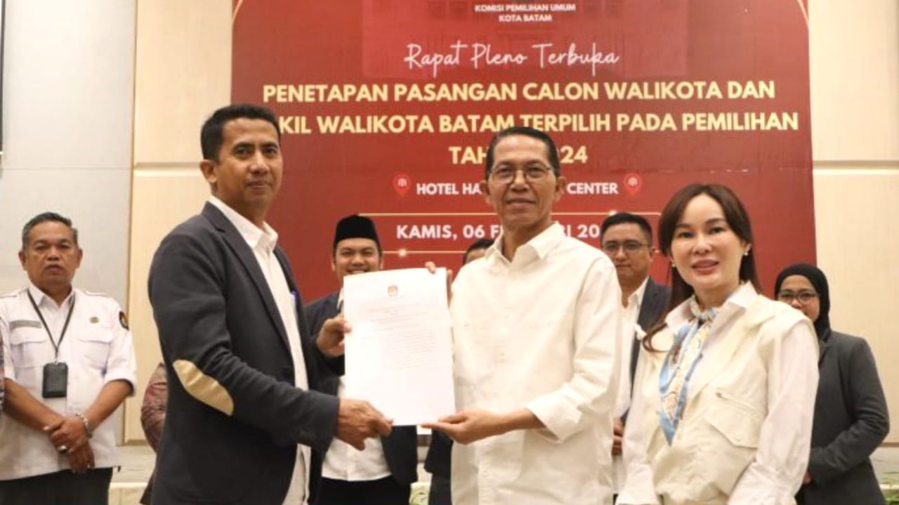 Ketua KPU Batam, Mawardi saat menyerahkan surat berita acara hasil rapat pleno terbuka penetapan pasanganan calon Walikota dan Wakil Walikota terpilih pada Pemilukada 2024 kepada Amsakar Achmad-Li Claudia Chandra di Hotel Harris Batam Center, pada Kamis (6/2).